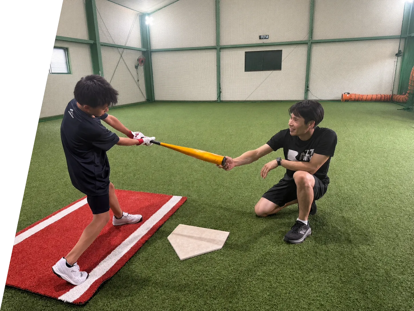 選手へバッティング指導を行うトレーナー